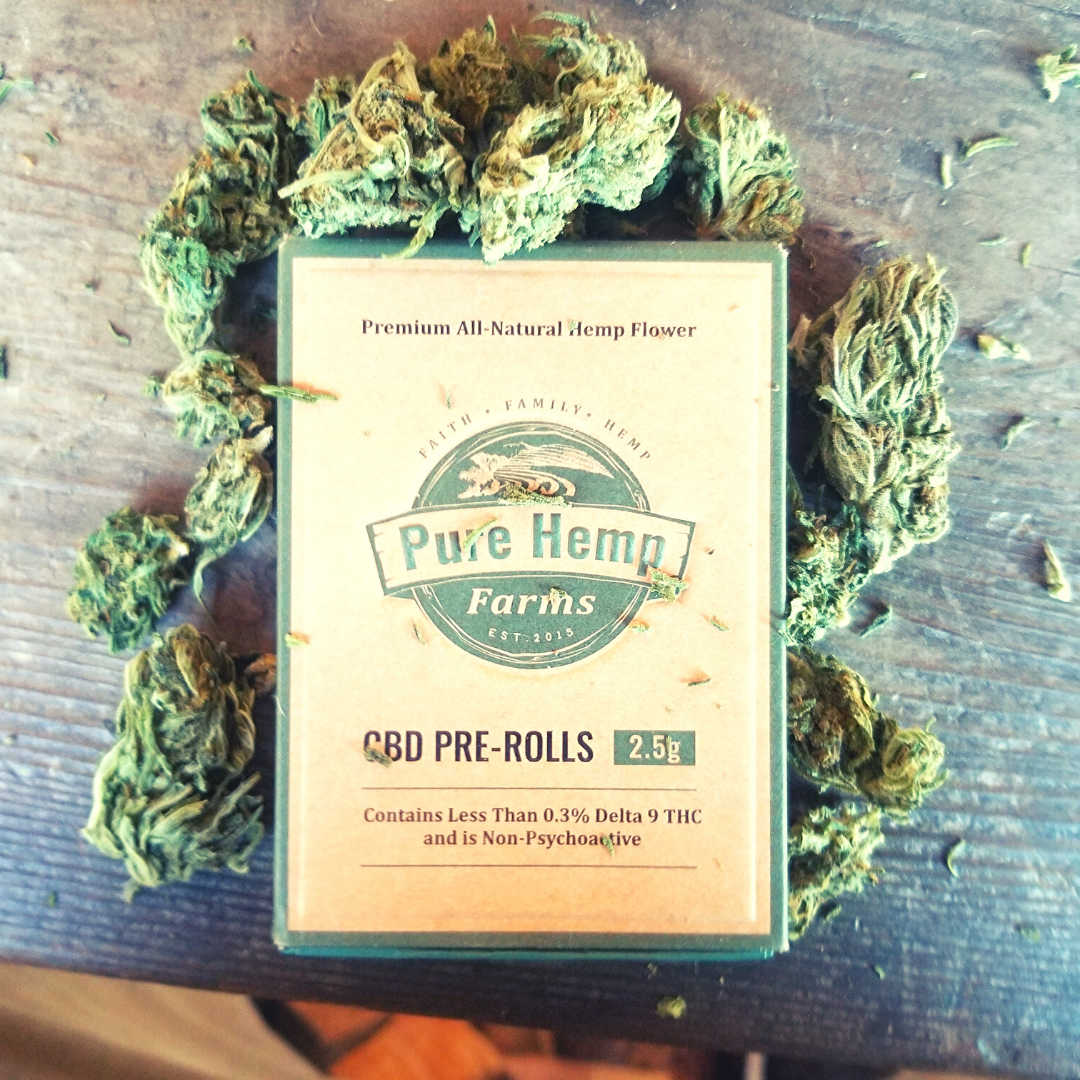 CBD Joints in a craft pre-roll box surrounded by Oregon-grown hemp flower buds. 